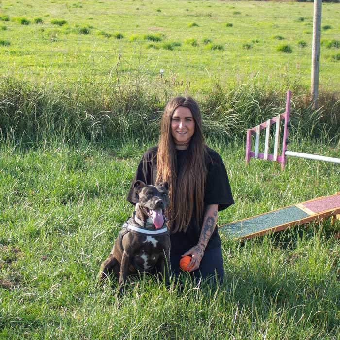 Sarah dog carer Jersey kneeling with happy dog